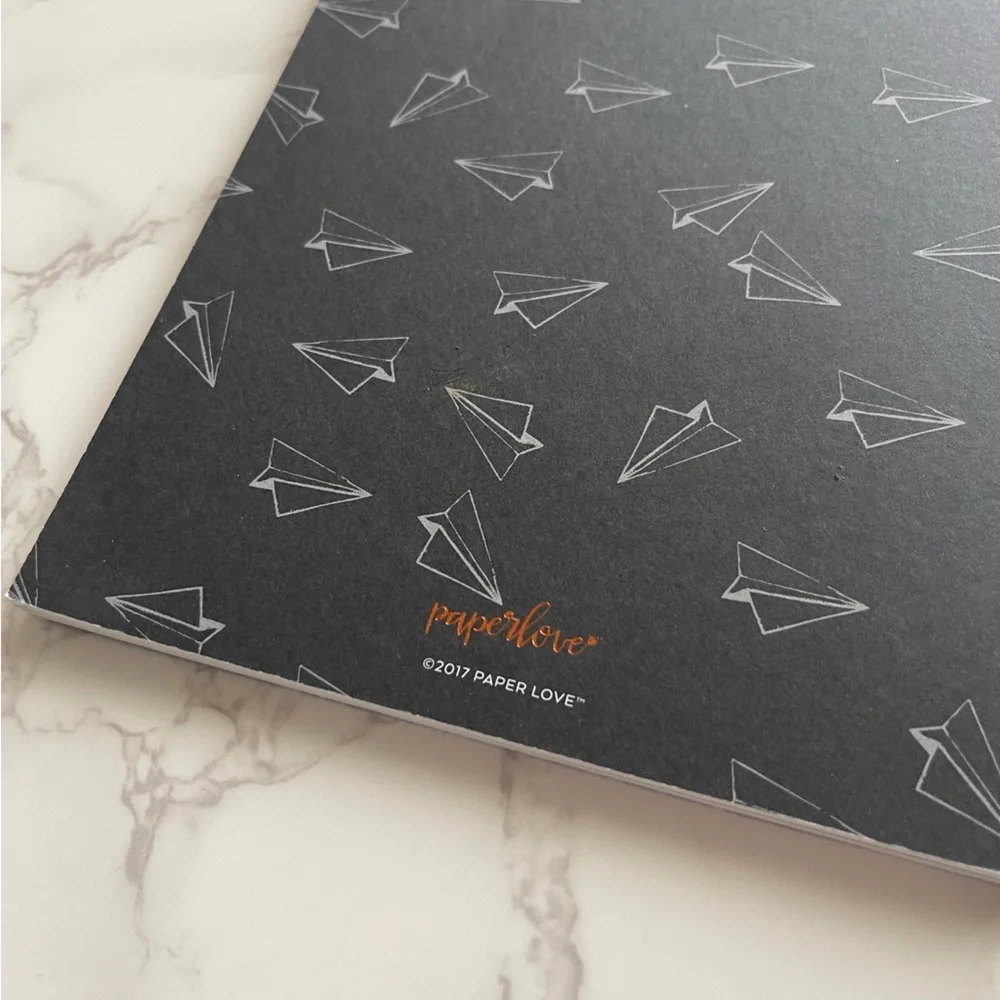 Notebook with paper airplane pattern on exterior and rose gold “NOTES” on front